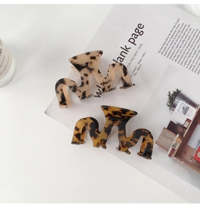 Detail showing wavy acetate hair claws in tortoise shell and amber patterns on a magazine