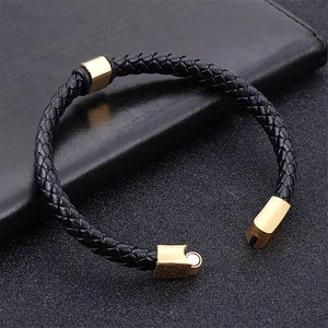 Bracelet pour homme en cuir tressé avec fermoir magnétique doré sur fond sombre texturé