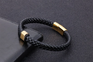 Détail d'un bracelet en cuir tressé noir avec fermoir magnétique doré sur cuir