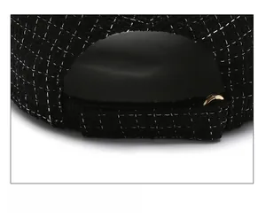 Detail of black tweed baseball cap featuring adjustable velcro strap and gold metal ring