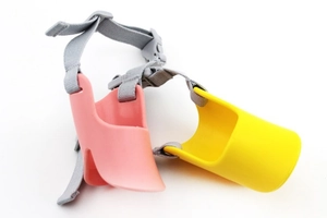 Detail of pink and yellow silicone duck-mouth dog muzzles with nylon straps