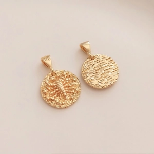 Detailed macro view of 14K gold-plated Scorpio zodiac and water ripple coin pendants