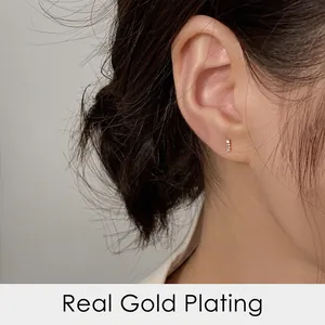 Elegant vertical gold plated stud earrings with four small crystals worn by a model