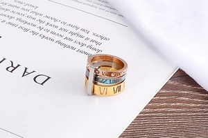 Detail of stacked Roman numeral rings with shell inlay and cubic zirconia stones