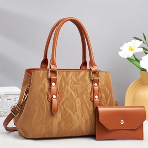 Detail of brown pleated leather tote bag with gold hardware and matching pouch bag