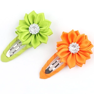 Detail of fabric flower hair clips with sparkling center rhinestones in green and orange