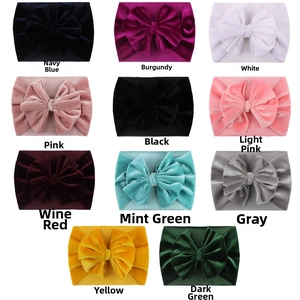 Flat lay of eleven colorful velvet bow headbands for babies on a clean white background