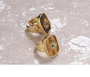 Close-up of adjustable gold rings with sun relief and natural gemstones on stone