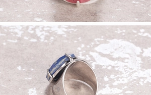Detail view of wide silver ring band featuring a raw blue lapis lazuli in claw setting