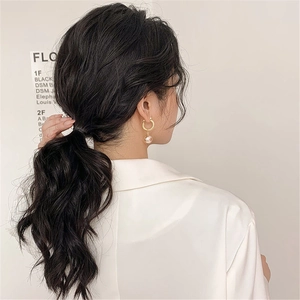 Close-up of elegant gold hoop earring with a large white pearl on model's ear