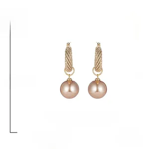 Detail shot of vintage golden hoop earrings with large champagne pearls and spiral texture