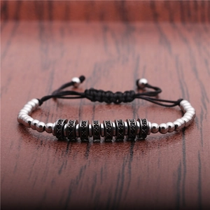 Macro detail of silver beads and black micro-inlaid zircon spacers on braided bracelet