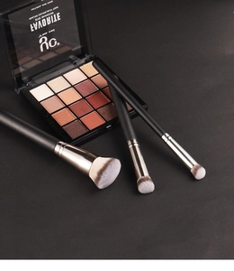 Three professional foundation brushes with a 16-color eyeshadow palette on black background