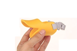 Close-up of a bright yellow duck-bill shaped silicone dog muzzle with adjustable strap