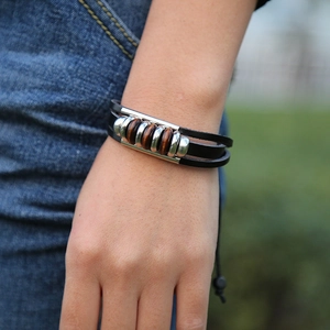 Detail of layered black leather bracelet with silver metal tubes and wooden beads