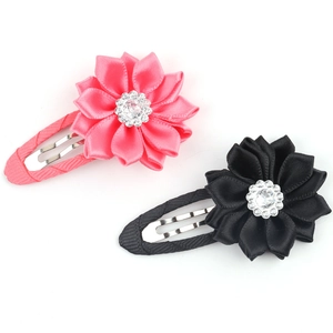 Close-up of fabric flower hair clips with rhinestones and fabric edges in pink and black