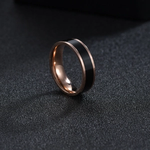 Detail of 6mm rose gold stainless steel ring with black enamel inlay on dark background
