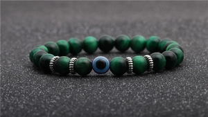 Detail of 8mm green tiger eye beads and evil eye charm on beaded men's bracelet