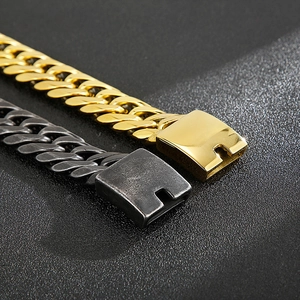 Macro detail of gold and charcoal curb bracelets with sturdy square buckles on black surface