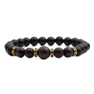 Detail of beaded bracelet with matte black beads, red stones, and gold accents