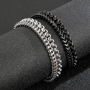 Detail of silver and black stainless steel layered Cuban chain bracelets for men