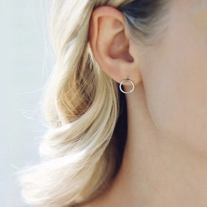 Boucles d'oreilles rondes argentées minimalistes portées par un mannequin pour l'échelle
