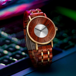 Luxury men's quartz watch with dark mahogany wood and gold accents on a laptop background