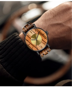Detail of zebra wood and black metal watch band with a brushed gold dial on wrist