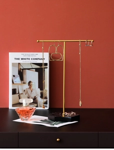 Detail of gold T-bar jewelry stand with black marble base holding necklaces and earrings