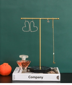 Detail of golden T-bar jewelry stand with hexagonal marble base and hanging earrings