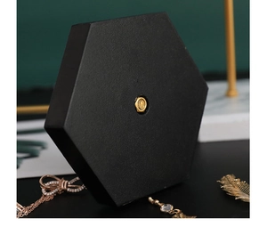 Detail of matte black hexagonal jewelry base with a gold metal fastener and textured finish