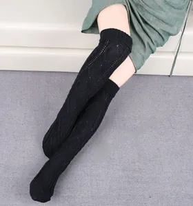 Close-up of black knitted over-knee leg warmers with hollow diamond crochet patterns