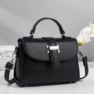Detail of black lychee texture handbag with silver lock and elegant orchid decoration