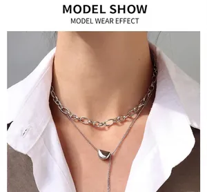 Detail of double-layered silver chain necklace with geometric bean pendant on model
