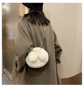 Detail of white plush bunny ear bag with gold ring handle and metal chain strap