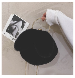 Detail of black faux fur bag with golden metal handle and sphere lock clasp mechanism