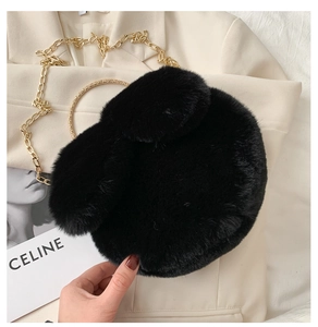 Detail of cute black plush rabbit bag with gold metal handle and elegant chain strap