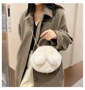 Close-up of white plush bunny ear handbag with gold metal ring handle and chain strap