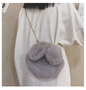 Detail of grey plush crossbody bag with bunny ears and a gold metal chain strap