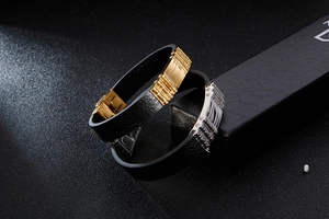 Dettaglio di bracciali da uomo in pelle con chiusure in metallo oro e argento su sfondo nero