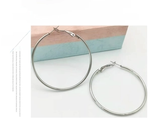 Close-up of polished stainless steel hoop earrings showing a sleek mirror finish surface