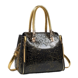 Luxury black tote bag with embossed gold floral pattern and cylindrical metal handles