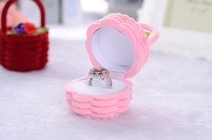 Pink velvet shell jewelry box featuring a colorful gemstone ring on a white cushion