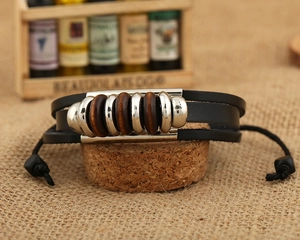 Detail of vintage multilayer braided leather bracelet with wooden beads and silver metal