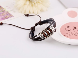 Detail of vintage multilayer braided leather bracelet with wooden beads and silver rings