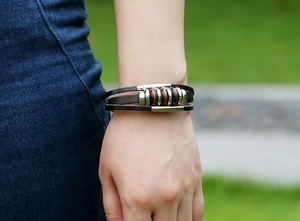 Detail of vintage multilayer brown leather bracelet with metal rings on a male wrist