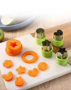 Close-up of 4 flower-shaped stainless steel vegetable cutters with green handles