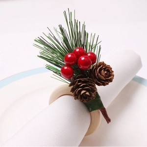 Detail of Christmas napkin ring featuring pine cones, red berries, and cedar on wooden loop