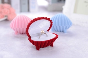 Macro shot of an open velvet shell jewelry box with rings in vibrant red and pink colors