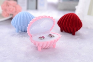 Pink shell-shaped velvet jewelry box showing interior earrings with blue and red options